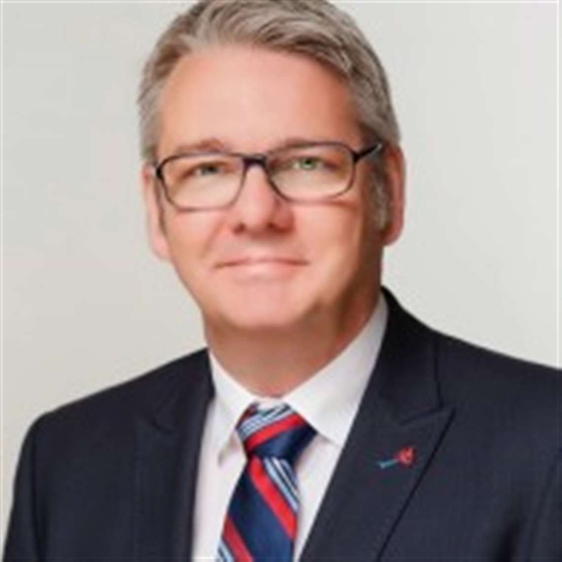 Jens Ennen, Tadano Faun and Tadano Demag CEO in a suit with blue-red-blue tie