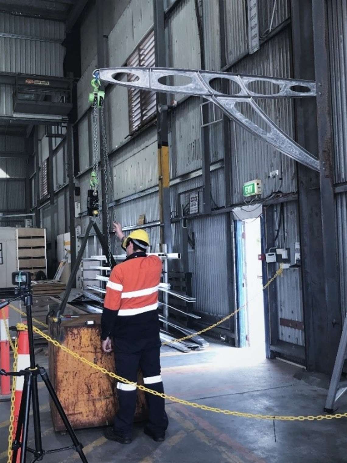 A steel test weight suspended from the assembled davit crane inside an Austal building