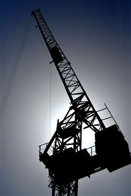 Jost tower crane luffed to a steep angle sihouetted on a blue sky