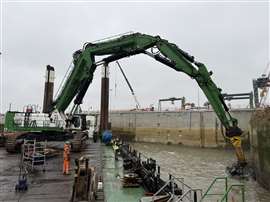 Une pelleteuse travaille dans le port à la démolition d'un mur de quai en béton