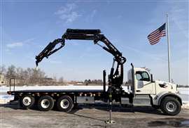 black Hiab loader crane behind the white cab of a US flat bed truck