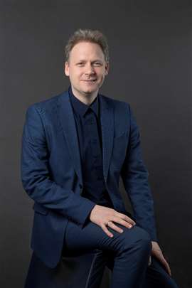 Wim Sarens con traje azul y camisa oscura.