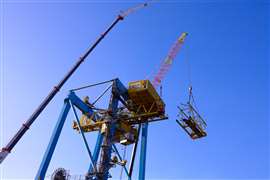 Two large Liebherr teleboom cranes from Somalev lifting together against a blue sky