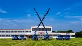 display of blue Fassi cranes with crossed booms in front of the factory