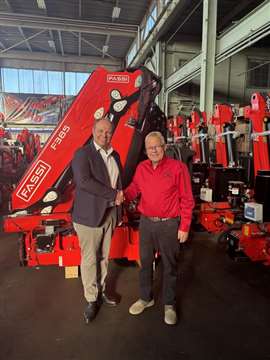 two men standing in front of red Fassi cranes shaking hands on the acquisition deal