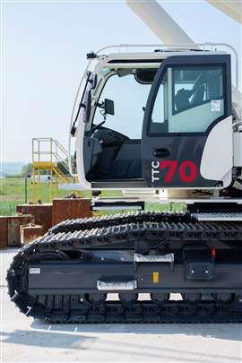 Seitenansicht eines weiß-grauen Terex TTC 70, Kabinentür geöffnet, Raupenfahrwerk