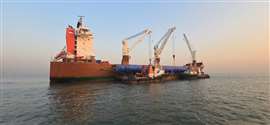 long blue process columns being transferred between ship and barge at sea