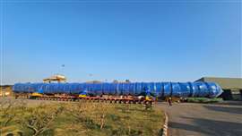mega long blue wrapped process column on a long row of self propelled modular transporter