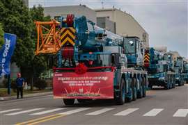 Sarens blue and yellow cranes from XCMG adorned with banners lined up to leave the factory