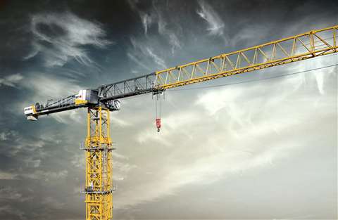 Yellow black and white flat top tower crane against a stormy sky