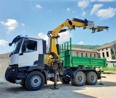 Yellow crane stretched out over the back of a green and white three axle rigid truck