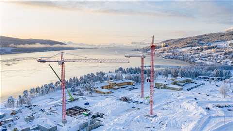 Red tower cranes against a snowy building site