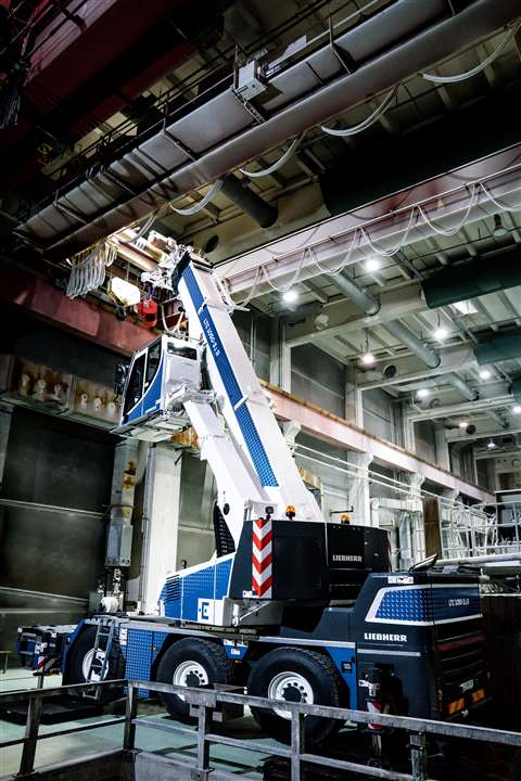 blue and white crane with the boom up inside an industrial building
