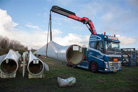 red loader crane on a blue tractor unit lifting a turbine blade