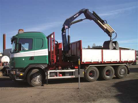 black crane with grab on green and white truck