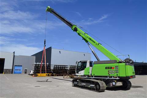 Green telescopic boom crane against a blue sky