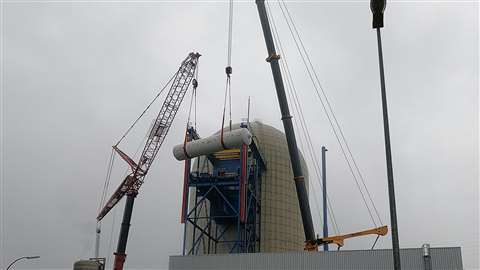 two cranes holding a horizontal tank, grey sky