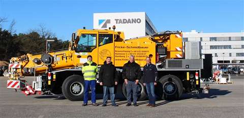 lineup of Tadano and Schmidbauer people standing in front of a yellow Tadano AC 3.045-1 City crane