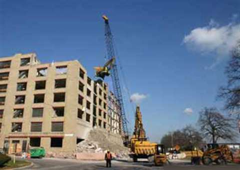 A 150-ton Liebherr crawler crane lifts a demolition excavator to the top of a building